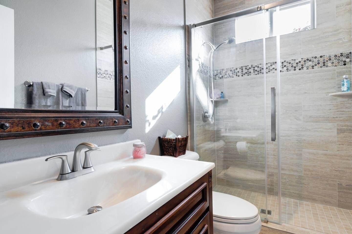 Hall bathroom with a dark vanity and a tiled shower