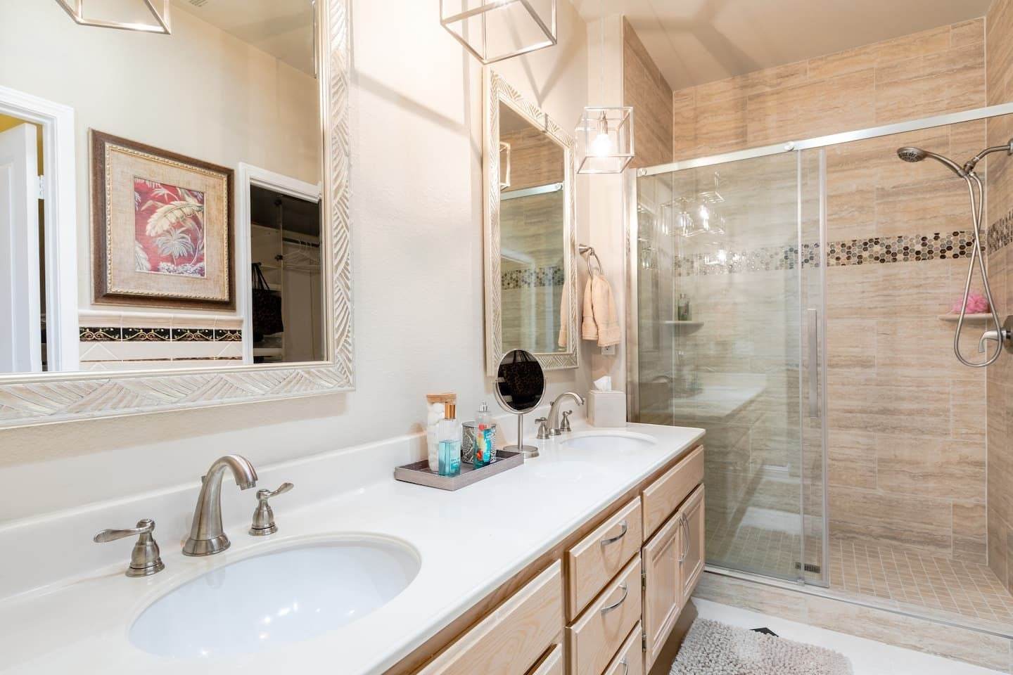 Primary bathroom with a double vanity, a large mirror and a tiled shower