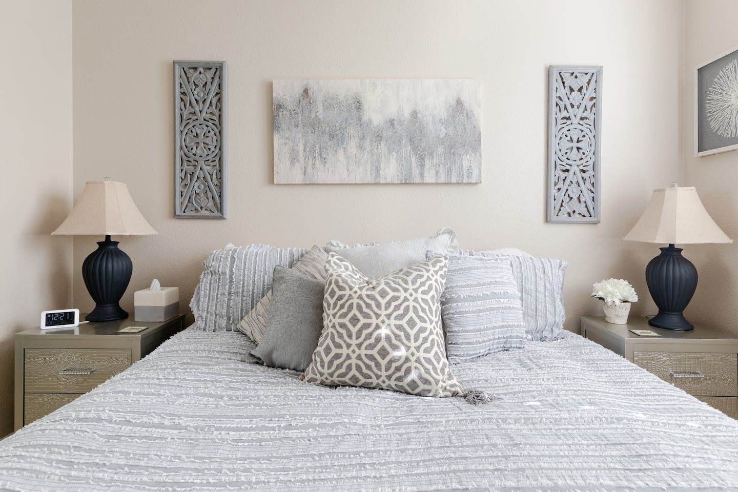 Bedroom 2: king bed with a gray comforter between two black lamps
