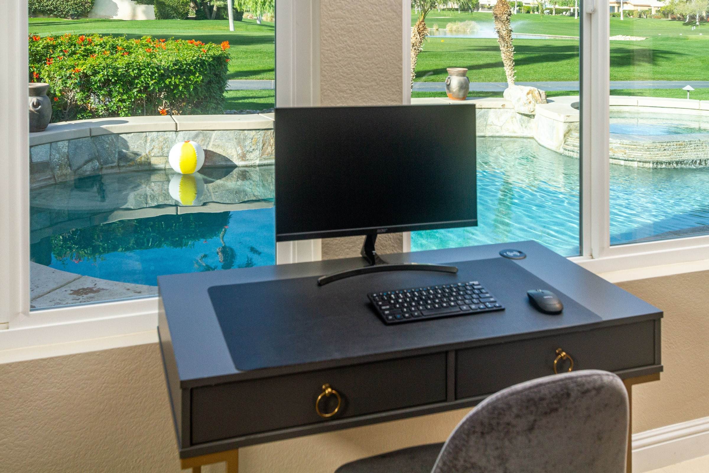 Desk with a monitor beside a window onto the pool