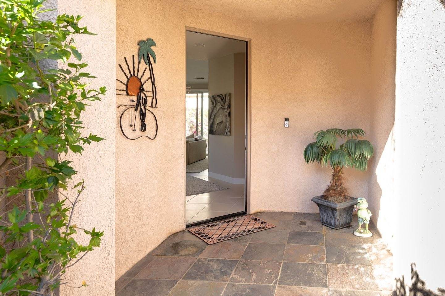 Front courtyard with the door open and a potted palm