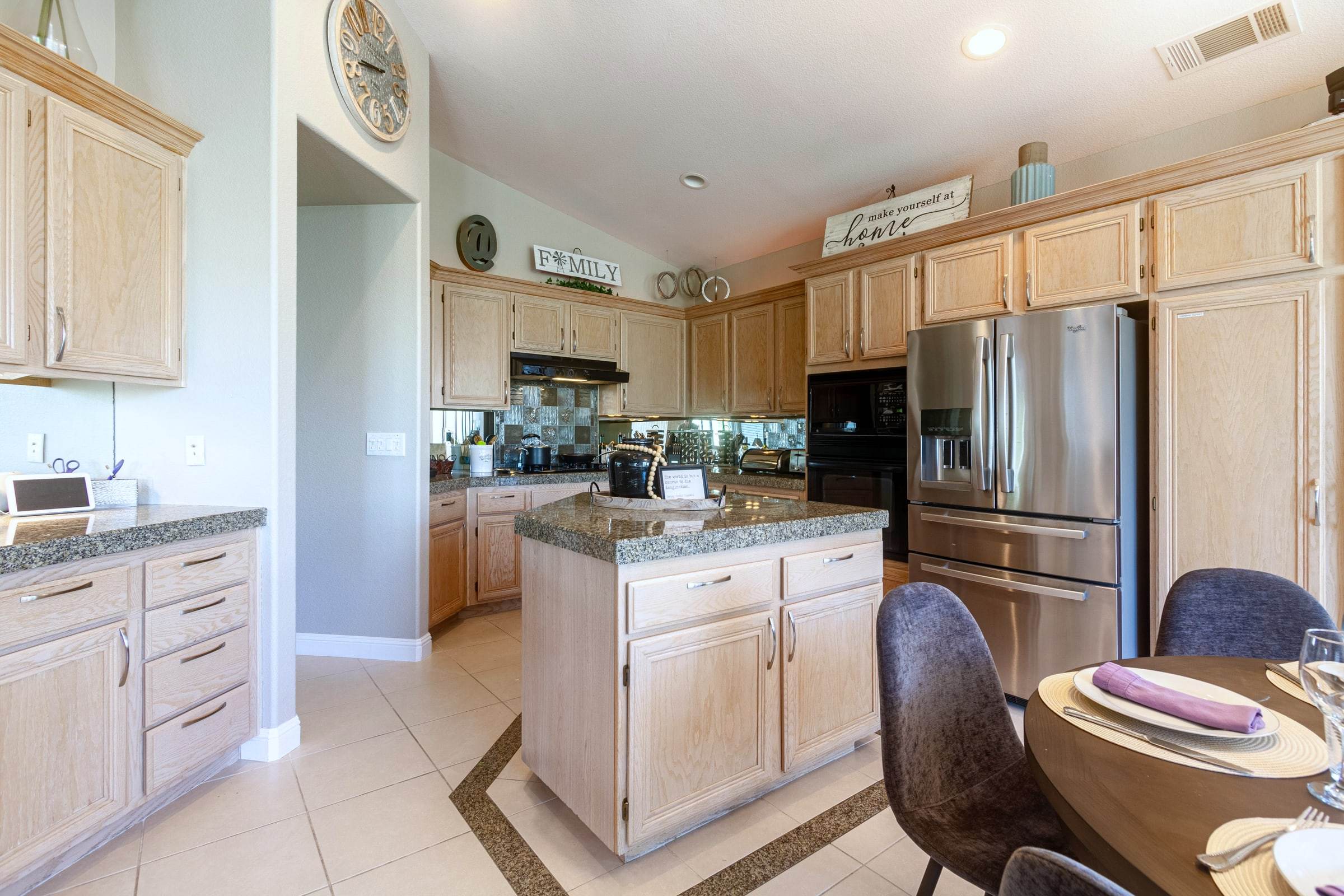 Kitchen with a center island, light wood cabinets, granite counters and a stainless refrigerator