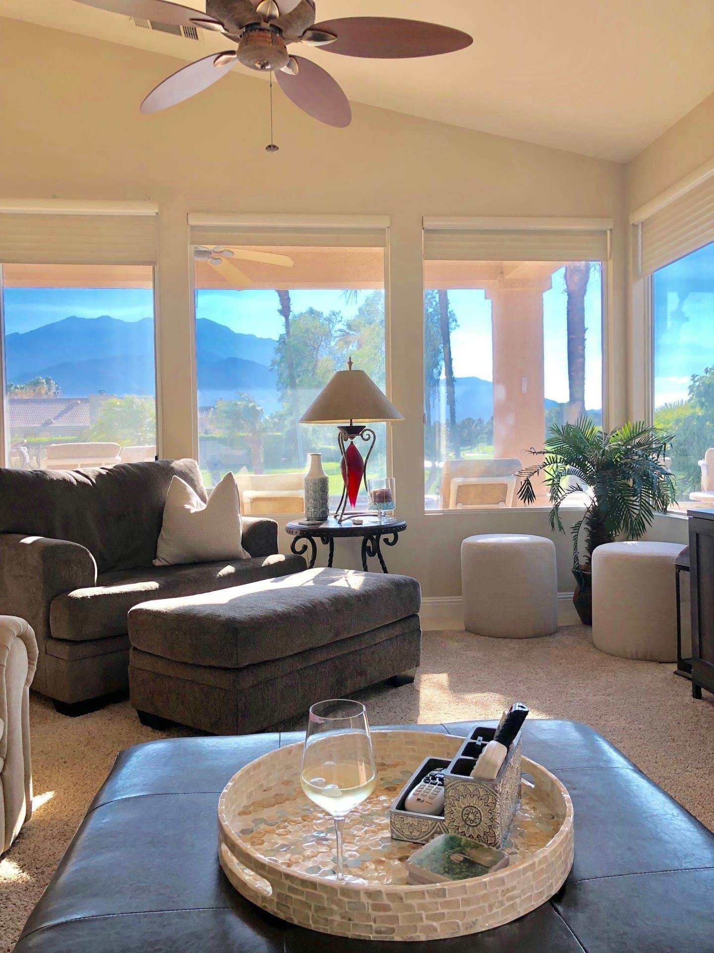 Armchair and ottoman by a wall of windows looking out to the patio and the mountains