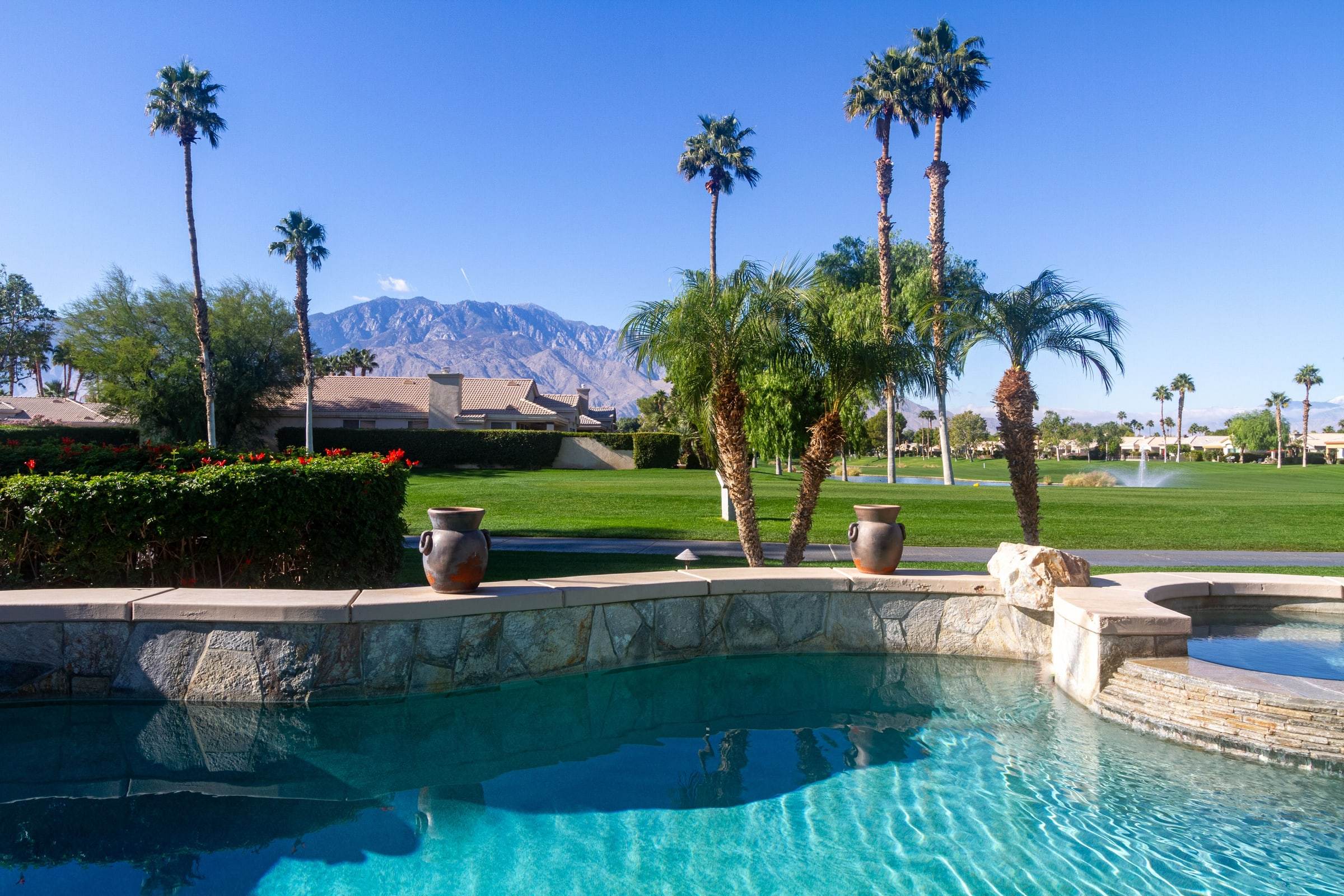 Edge of the pool with palm trees, the golf course and snow on the San Jacinto mountains
