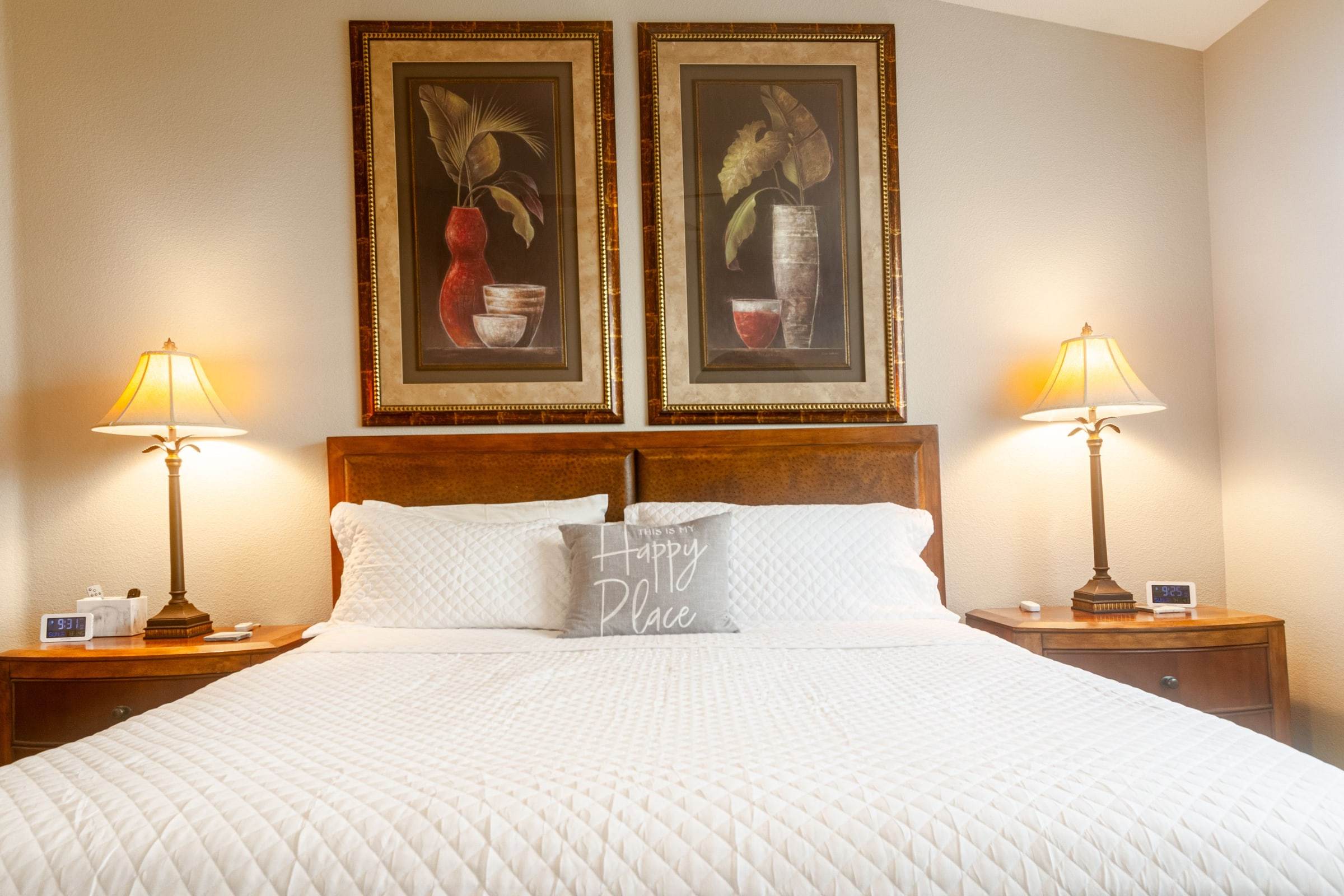 Primary bedroom: king bed with white bedding, matching lamps and two framed prints