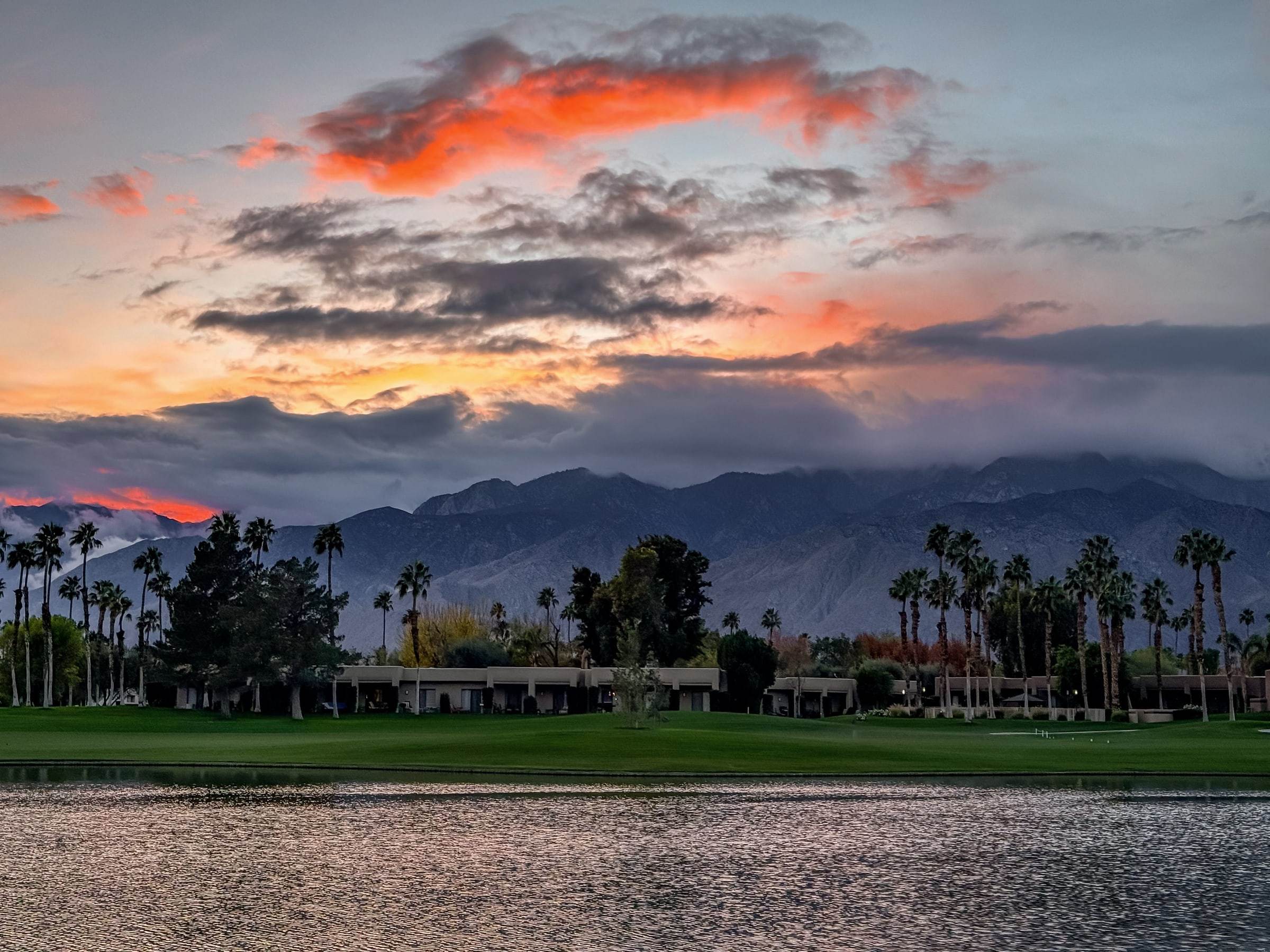 Sunset clouds over the mountains, reflected in a golf-course pond